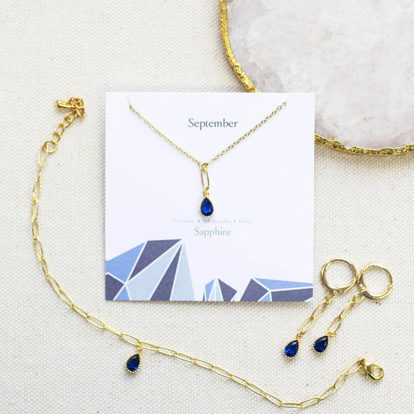 Image shows Dainty Teardrop Birthstone Jewellery Set in September Sapphire on a birthstone characteristics card.