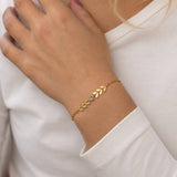 Gold plated vine birthstone bracelet with a light blue crystal, styled with a classic white top for everyday wear
