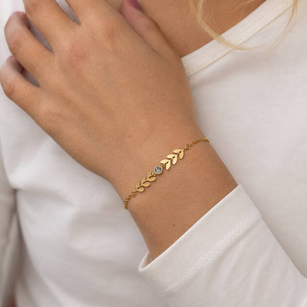 Gold plated vine birthstone bracelet with a light blue crystal, styled with a classic white top for everyday wear