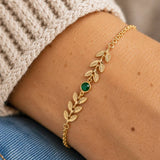 Gold plated vine birthstone bracelet with emerald crystal, styled on the wrist for an elegant layered jewellery look