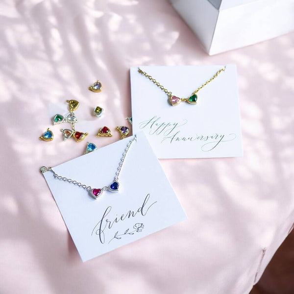 Double crystal heart charm link necklace shown in gold and silver displayed on the 'friend' and 'Happy Anniversary' sentiment cards.