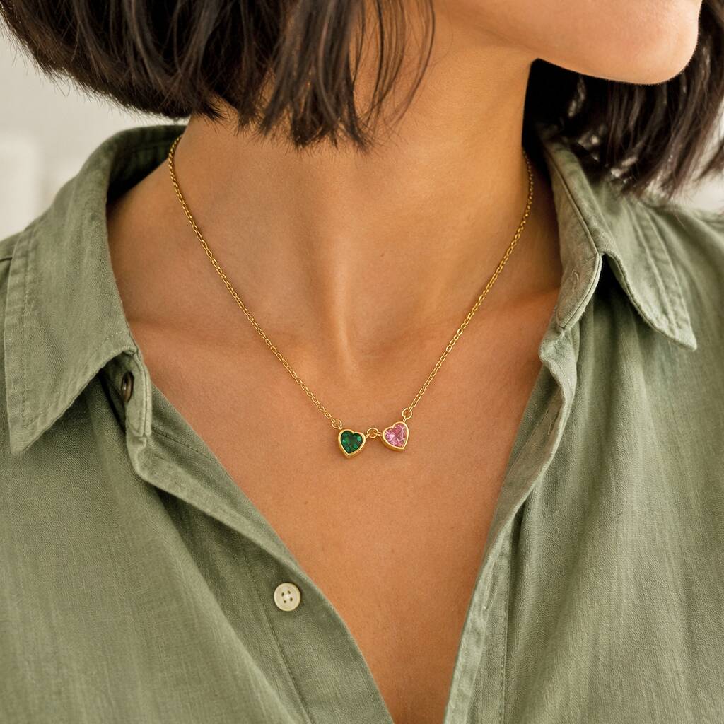Gold heart birthstone necklace with green and pink crystal charms styled with an everyday outfit