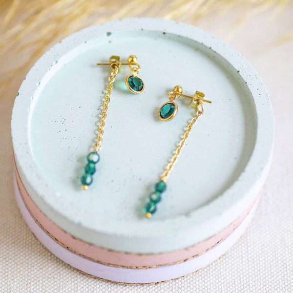 Image shows Double Drop Birthstone Chain Earrings in May Emerald on a white backdrop.