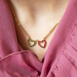 Image shows gold double birthstone heart necklace worn with a pink frill top.