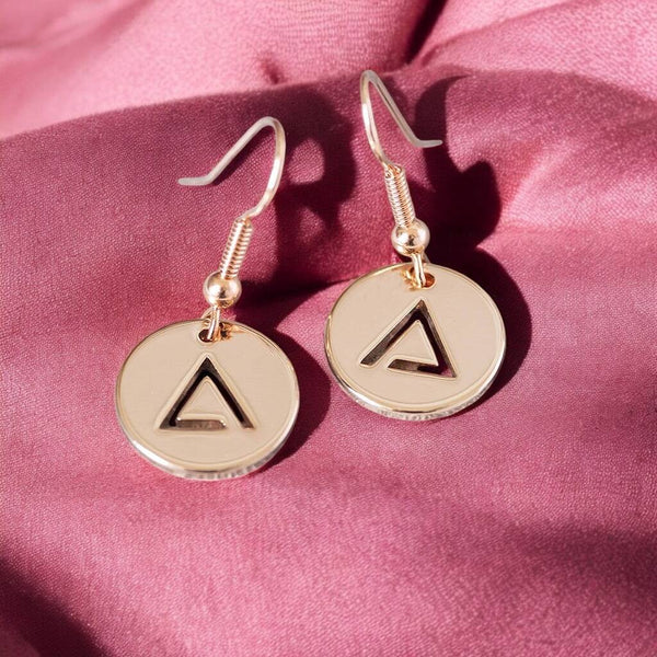 image shows rose gold fire element earrings presented on a pink background