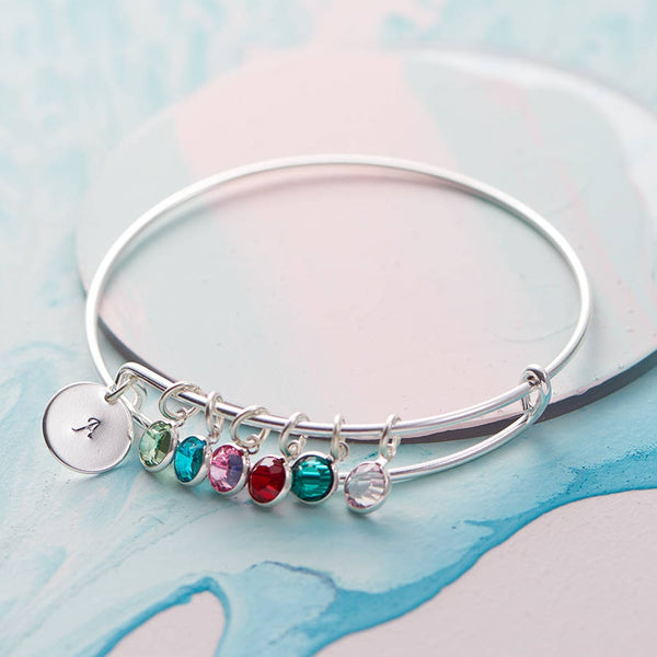 Image shows a silver plated family birthstone bangle with initial A charm and August, December, October, July, May and June birthstone charms