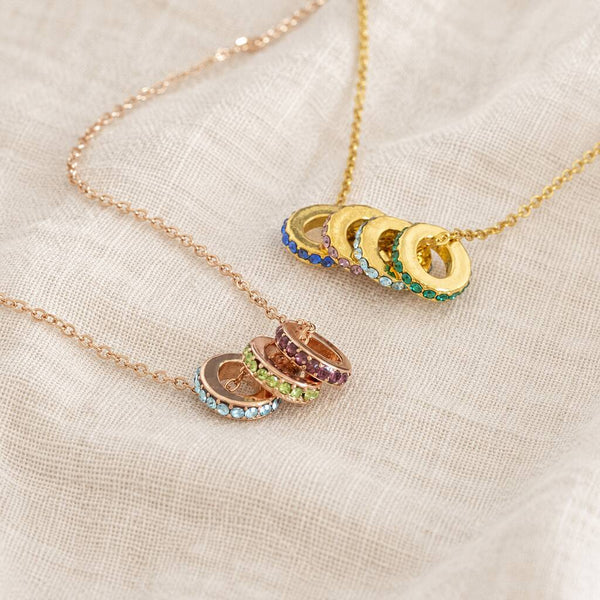 Colourful birthstone ring necklaces in gold and rose gold, featuring stacked crystal ring charms