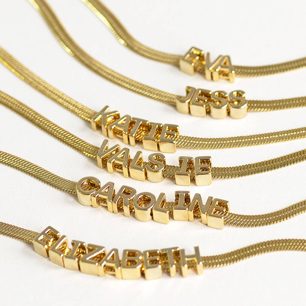 Gold flat chain name bracelets displayed with gold chunky initials that move freely along the bracelet