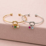 Gold and silver friendship knot bangles displayed together with colourful heart birthstone charms for everyday styling