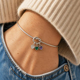 Silver friendship knot bangle styled with three sparkling heart birthstone charms for a colourful stacked jewellery look