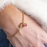 Image shows model in white fluffy jumper wearinga friendship knot bracelet with July Ruby birthstone heart charm