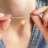 Image shows model in denim shirt wearing a an orange pumpkin necklace
