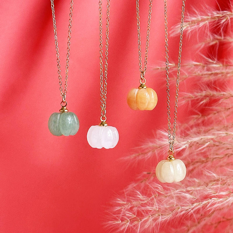 Image shows halloween pumpkin necklaces suspended in front of an orange background 