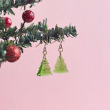 Images shows glass christmas tree earrings hanging from a mini christmas tree branch