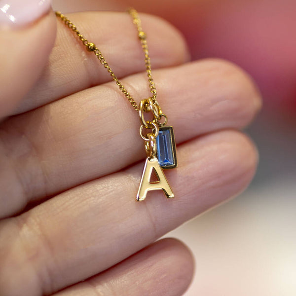 Gold initial necklace with baguette birthstone on satellite chain