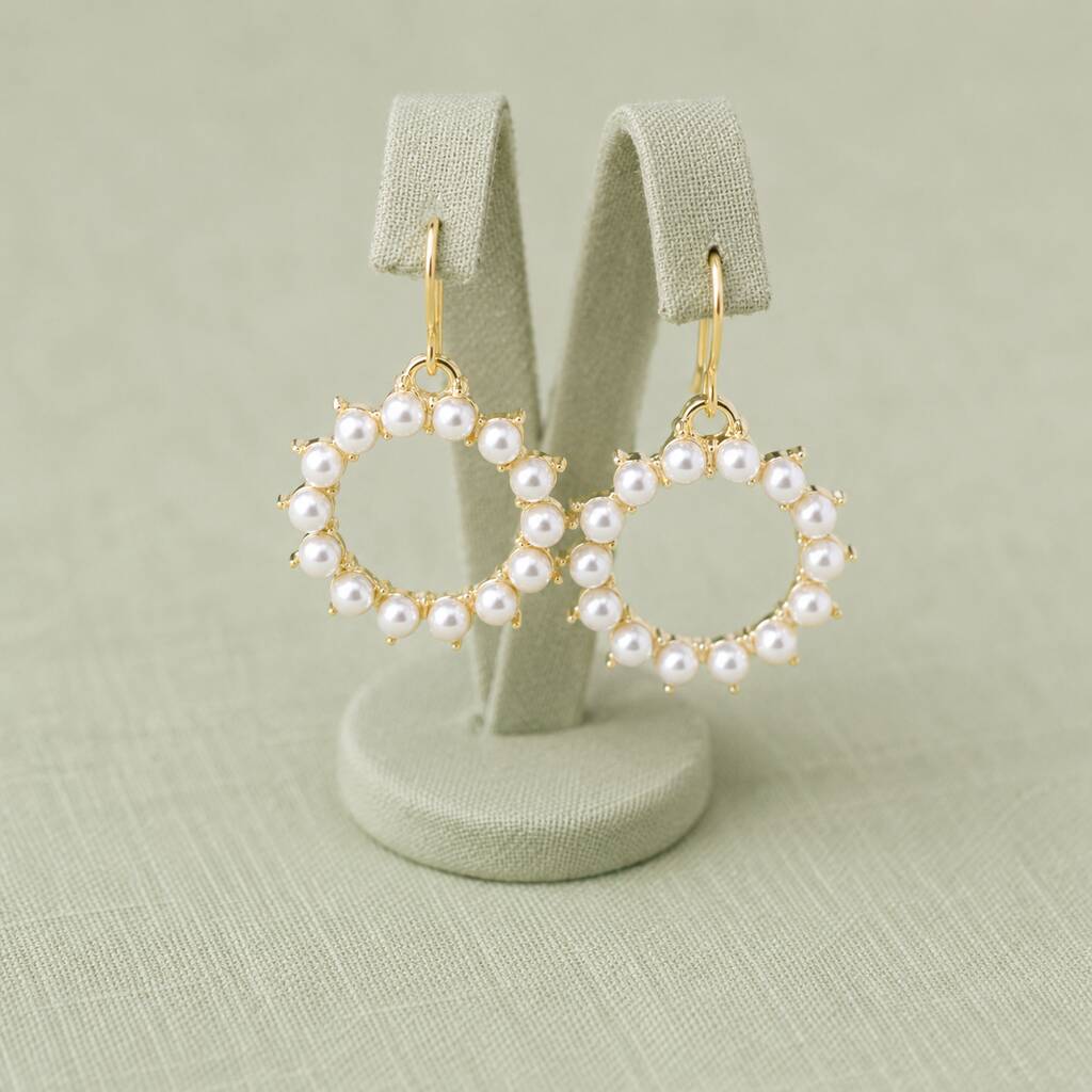 Pearl sunburst drop earrings showcased on a display stand, highlighting their delicate handcrafted appearance

