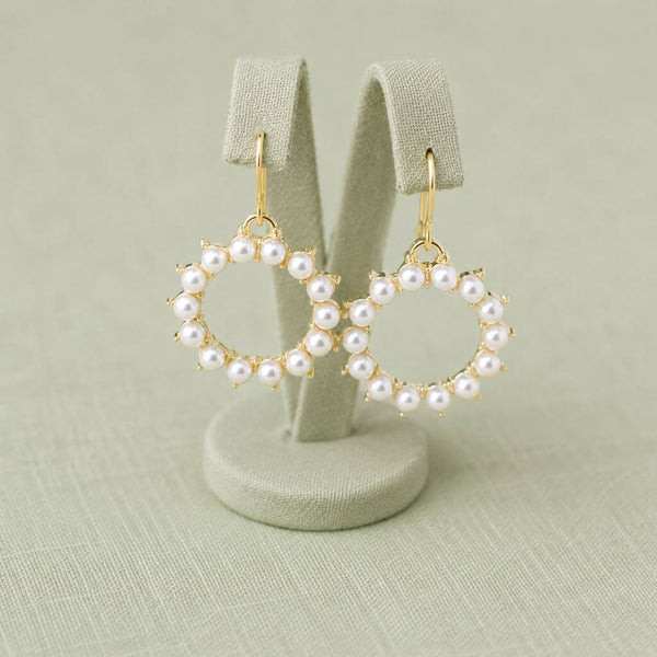 Pearl sunburst drop earrings showcased on a display stand, highlighting their delicate handcrafted appearance
