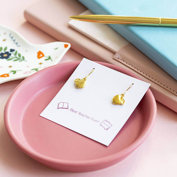 Gold apple drop earrings presented on a Best Teacher Ever! sentiment card and displayed on a pink trinket dish.