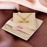 Crystal T bar pendant necklace displayed in JOY packaging, featuring a sleek gold plated design with sparkling detail