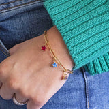 Image shows Model in a green jumper wearing a Gold Plated Family Birthstone Stars Bracelet with July, March and February birthstones.