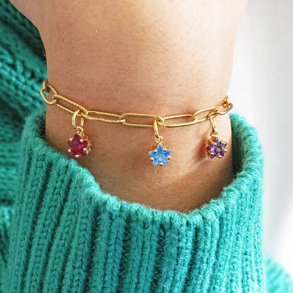 Image shows Model in a green jumper wearing a Gold Plated Family Birthstone Stars Bracelet with July, March and February birthstones. 