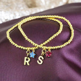 Image shows Gold Plated Initial and Birthstone Star Bracelets with the initial 'R' and September Sapphire star birthstone and  initial 'S' and July Ruby star birthstone.