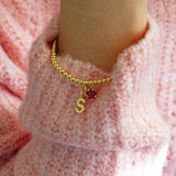 Model wears Gold Plated Initial and Birthstone Star Bracelet with the initial 'S' and July Ruby star birthstone.