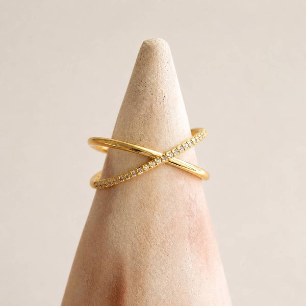 Gold plated crossover ring with pavé crystal detail on a display stand, perfect for stacking and everyday styling