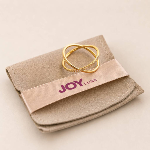 Gold plated crossover ring with pave crystal accents displayed on a soft jewellery pouch for elegant styling shots