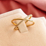 Gold plated crossover ring with pave crystal detail, styled on a soft jewellery display for elegant ring stacking looks