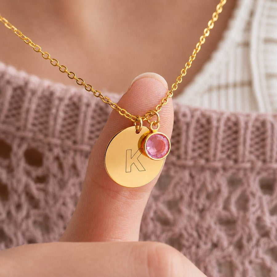 Layered gold plated initial birthstone disc necklaces with colourful crystal charms, personalised charm jewellery styling.