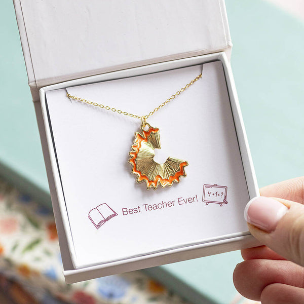 A gold plated necklace with pencil shaving charm trimmed in gold presented in a gift box on a Best Ever Teacher sentiment card.