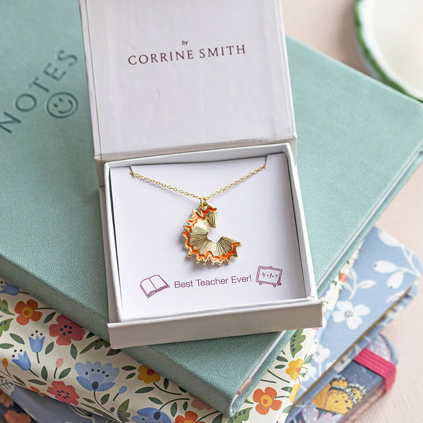 Gold pencil shaving pendant necklace presented in gift box on notebooks, stylish teacher-inspired jewellery gift