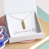 A gold plated dainty ruler charm necklace presented on a Best Teacher Ever! sentiment card inside a Joy by Corrine Smith gift box.