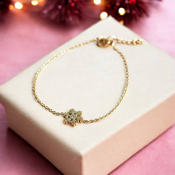 Gold snowflake bracelet presented on a cream coloured jewellery box.