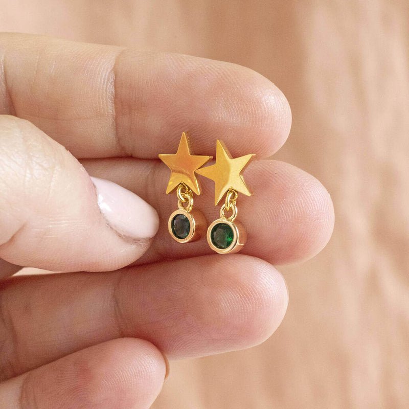 Model holds Gold Plated Star Birthstone Earrings with May emerald birthstone.