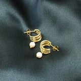 Image shows Gold Plated Triple Hoop Pearl Earrings on a green backdrop.