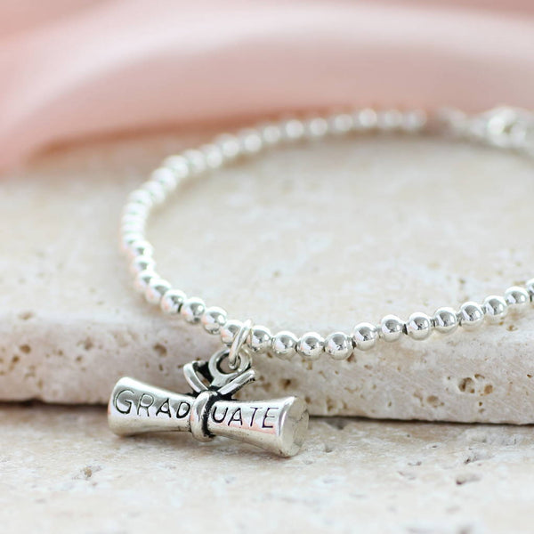 Detailed silver plated graduation scroll charm on a beaded stretch bracelet, perfect for stacking and everyday style