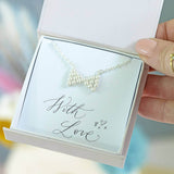 Model holds a silver plated Hand Beaded Pearl Bow Necklace on a 'with love' sentiment card in a JOY by Corrine Smith gift box.