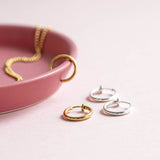 Gold and silver hoops earrings for non pierced ears displayed on a pale pink background