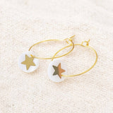 Image shows gold hoop earrings with a Mother of Pearl round disc featuring a gold star.