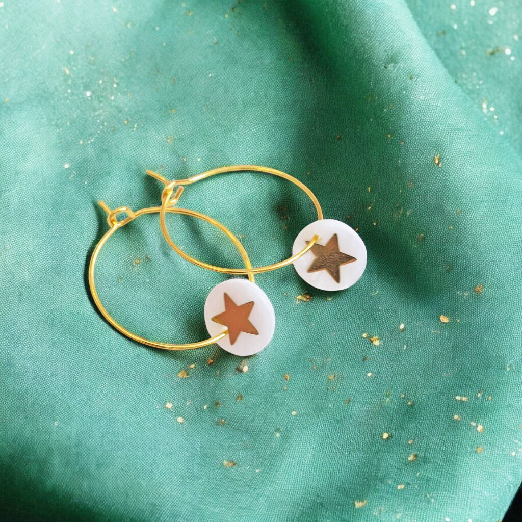 Image shows gold hoop earrings with a Mother of Pearl round disc featuring a gold star.