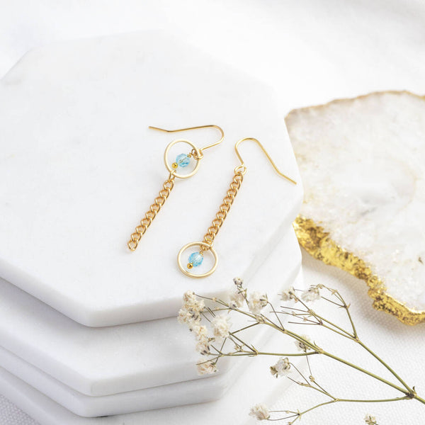 Image shows Mismatched Birthstone Circle Chain Drop Earrings with the March Aquamarine birthstone on a white display backdrop.