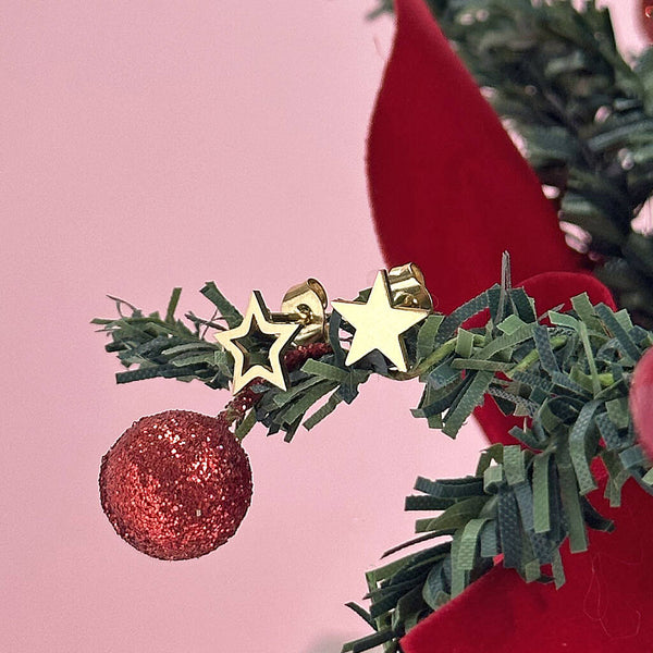 Image shows mismatched gold star earrings on a mini christmas tree