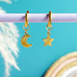 Image shows Moon And Star Huggie Hoop Earrings hanging in front of a turquoise background