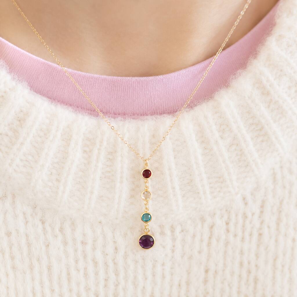 Gold birthstone drop necklace with four colourful crystal charms, styled with a cosy cream knit jumper