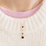 Gold birthstone drop necklace with four colourful crystal charms, styled with a cosy cream knit jumper