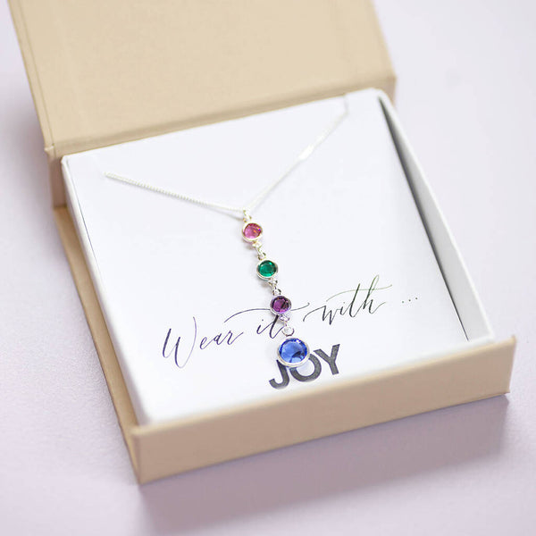 Silver birthstone drop necklace with four colourful crystal charms displayed in JOY gift box packaging