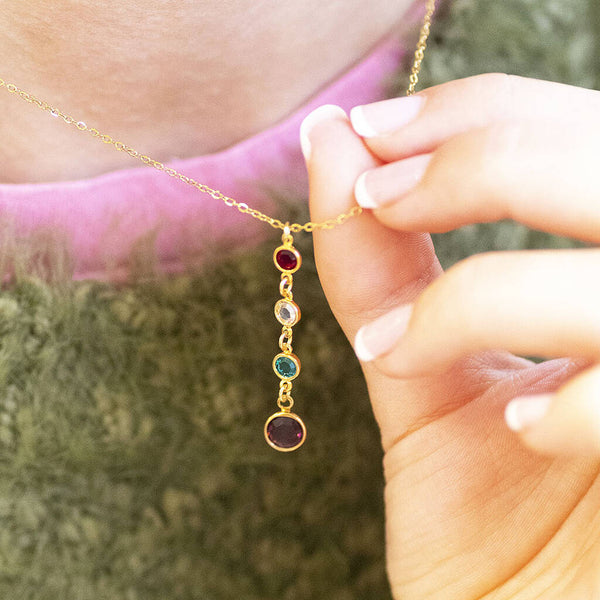 Gold birthstone pendant necklace with four colourful crystal drops styled on a cosy knitted outfit