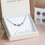 Mother and two children gold round birthstone bracelet presented on a calligraphy written sentiment card with the word family and in a Joy by Corrine Smith branded gift box. 
